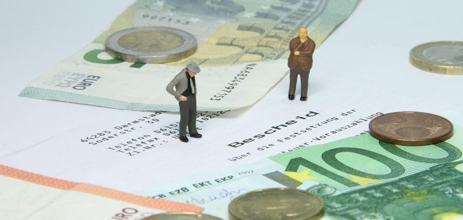 zwei kleine Männchen die auf Geldscheinen stehen