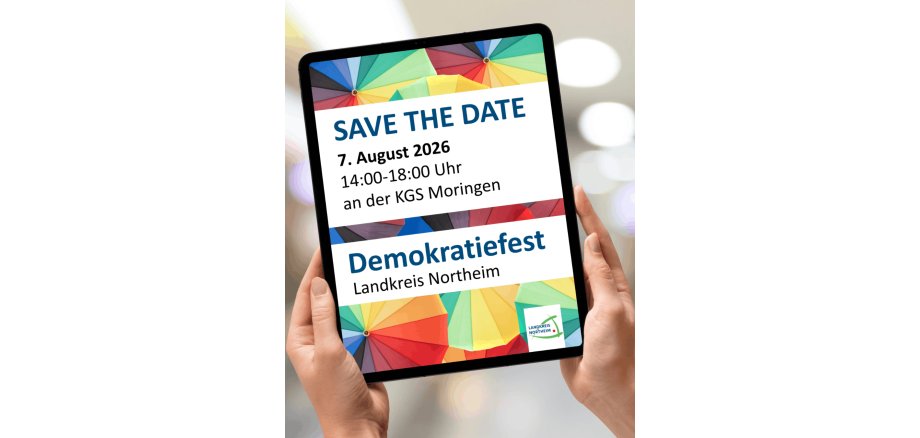 Ein Tablett das mit zwei Händen gehalten wird, wo drauf steht das am 07 August Demokratiefest stattfindet