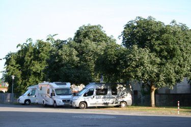 Ein Bild vom Wohnmobilstellplatz in Moringen. Man sieht drei Wohnmobile unter Laubbäumen