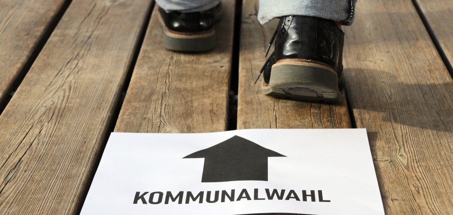 Ein Schild mit dem Aufdruck Kommunalwahl und Füße